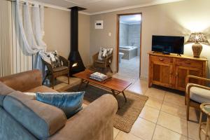 sala de estar con sofá y TV en Hazenjacht Karoo Lifestyle - Die Melkstal, en Oudtshoorn