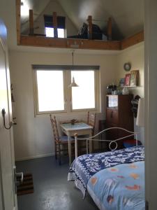 a bedroom with a bed and a table and two windows at Het Pulletje in Westzaan