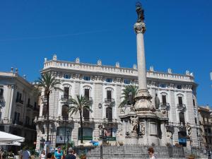 ein Gebäude mit einer Statue auf einer Säule davor in der Unterkunft Prince Moncada in Palermo