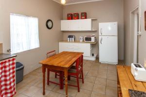 a kitchen with a wooden table and a refrigerator at Hazenjacht Karoo Lifestyle - Oom Manus se Huis in Oudtshoorn