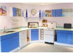 a kitchen with blue cabinets and white appliances at 7 Whinlands in Thorpeness
