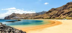 a beach with people on it with mountains in the background at Apartamentos Ester in Santa Cruz de Tenerife