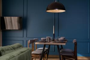 a dining room with a table and a blue wall at Elite Apartments Oliwa Martinique in Gdańsk