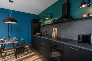 a kitchen with blue walls and a table with chairs at Elite Apartments Oliwa Martinique in Gdańsk