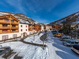 a snowy street with cars parked in the snow at Madame Vacances Les Balcons Du Viso in Abriès