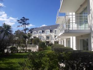 um grande edifício branco com varanda e arbustos em appartement bord de mer em Fouesnant