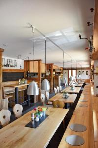 une salle à manger avec des tables en bois et des chaises blanches dans l'établissement Höhengasthaus Kolmenhof an der Donauquelle, à Furtwangen im Schwarzwald