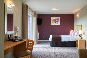 ロンドンにあるアントワネット ホテル ウィンブルドンのベッドとデスクが備わるホテルルームです。
