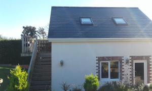a white house with a black roof and stairs at Garden View Apartment in Salcombe