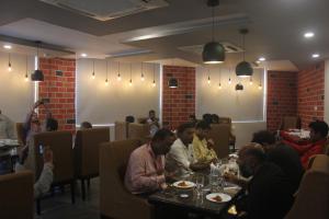 um grupo de pessoas sentadas numa mesa num restaurante em The Blue Lagoon Hotel Premium em Cuttack