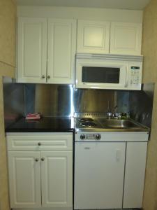 a kitchen with white cabinets and a sink and a microwave at North Vancouver Hotel in North Vancouver