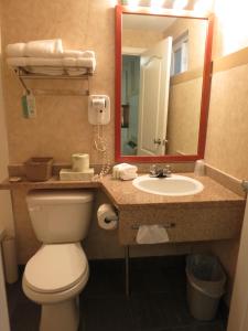 a bathroom with a toilet and a sink and a mirror at North Vancouver Hotel in North Vancouver