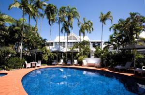 a swimming pool in front of a resort with palm trees at Ramada By Wyndham Cairns City Centre in Cairns