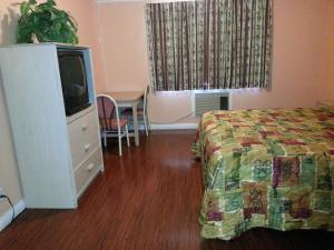a bedroom with a bed and a tv and a table at Travel Inn in Los Angeles