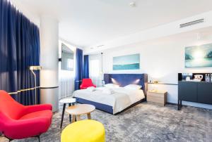 クラクフにあるキューバス ホテル クラクフのベッドと赤い椅子が備わるホテルルームです。