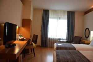 a hotel room with a bed and a desk and a television at Surmeli Istanbul Hotel in Istanbul