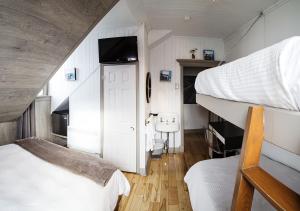 a bedroom with two bunk beds and a tv at Le Littoral Bistro Gourmand et Auberge in Sainte-Anne-des-Monts