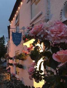 un edificio con flores y un cartel en él en Bay View Guest House, en Beer