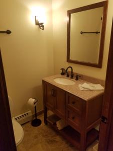 y baño con lavabo, aseo y espejo. en Ski In/Out Trailside Townhome, en Killington