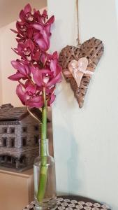 a vase with purple flowers and a heart on a wall at Affittacamere Cà Marcello in Monselice