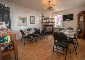 a dining room with tables and chairs and a chandelier at Le Littoral Bistro Gourmand et Auberge in Sainte-Anne-des-Monts