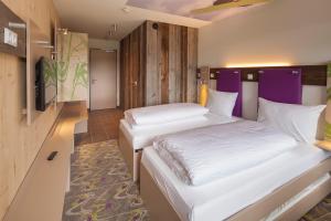 two beds in a room with purple walls at Explorer Hotel Montafon in Gaschurn