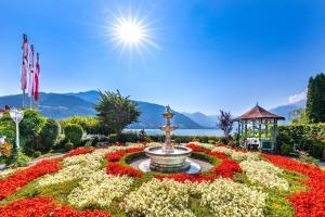 a fountain in a flower garden with a gazebo at Grand Hotel Zell am See in Zell am See