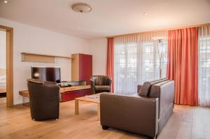 a living room with a couch and chairs and a television at Apartment Stotzhalten 3.5 - GriwaRent AG in Grindelwald