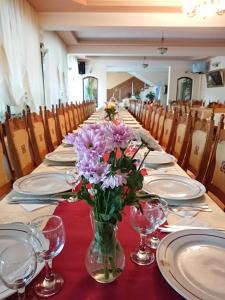 a long table with plates and flowers in a vase at Pensiunea Mușatinii in Putna +82 photos