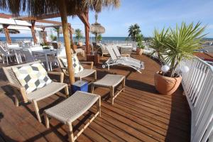 une terrasse en bois avec des chaises et des tables et l'océan dans l'établissement Bleu Mer Duplex & Suites, à Saint-Cyprien