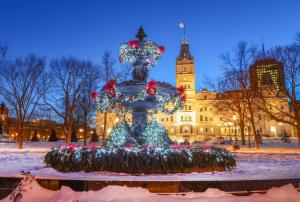 a fountain with christmas lights in front of a building at Hotel Universel in Quebec City