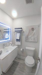 a white bathroom with a toilet and a sink at Pompano Beach Hidden Gem in Pompano Beach