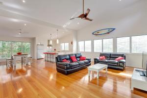 a living room with two couches and a kitchen at Sandyfeet House in Rainbow Beach