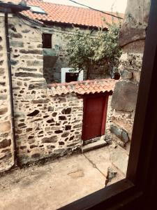 un bâtiment en pierre avec une porte rouge et un toit rouge dans l'établissement The Stone Boat Guesthouse for Pilgrims, à Rabanal del Camino