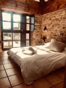 a large bed in a room with a stone wall at The Stone Boat Guesthouse for Pilgrims in Rabanal del Camino