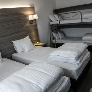 a group of three beds in a hotel room at Pensiunea Negoiu in Porumbacu de Sus