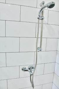 een douche met een slang in een witte badkamer bij Villa Gamini in Hikkaduwa