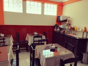comedor con 2 mesas y cocina en Pumas Cusco Hotel, en Cusco