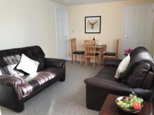 a living room with a leather couch and a table at Windmill Cottage in Worthing