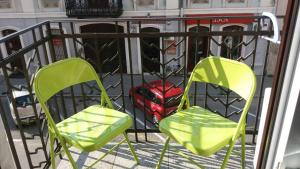two green chairs and a red suitcase on a balcony at Ergzotic Apartments & Room in Sombor