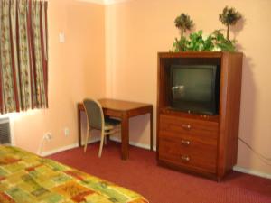 a hotel room with a tv and a desk and a table at Travel Inn in Los Angeles