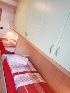 um pequeno quarto com duas camas e armários em Casa Paola em Pozza di Fassa