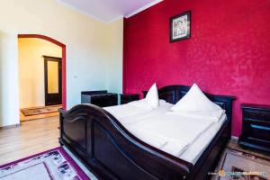 een slaapkamer met een bed met een rode muur bij Pensiunea Onix in Făgăraş