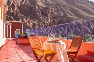 a table and chairs on a balcony with a mountain at Monkey Fingers House by Fatima mellal in Tinerhir