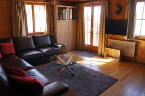 a living room with a couch and a glass table at Chalet Berken in Ernen