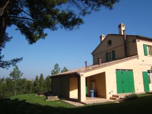 an old house with a green door in a yard at Agriturismo I Ciliegi del Checco in San Marcello