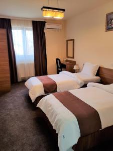 Habitación de hotel con 3 camas y escritorio. en Villa Lotus en Deva