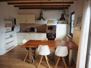 - une cuisine avec une table en bois et des chaises blanches dans l'établissement Ferienhaus Mundan 2, à Burhave