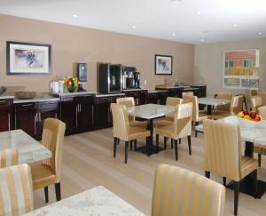 ein Esszimmer mit Tischen und Stühlen sowie eine Küche in der Unterkunft Paradise Inn and Suites Redwater in Redwater