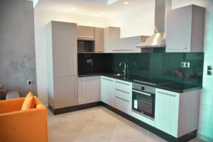 a kitchen with white cabinets and an orange chair at Honor Appart Hotel in Fnidek